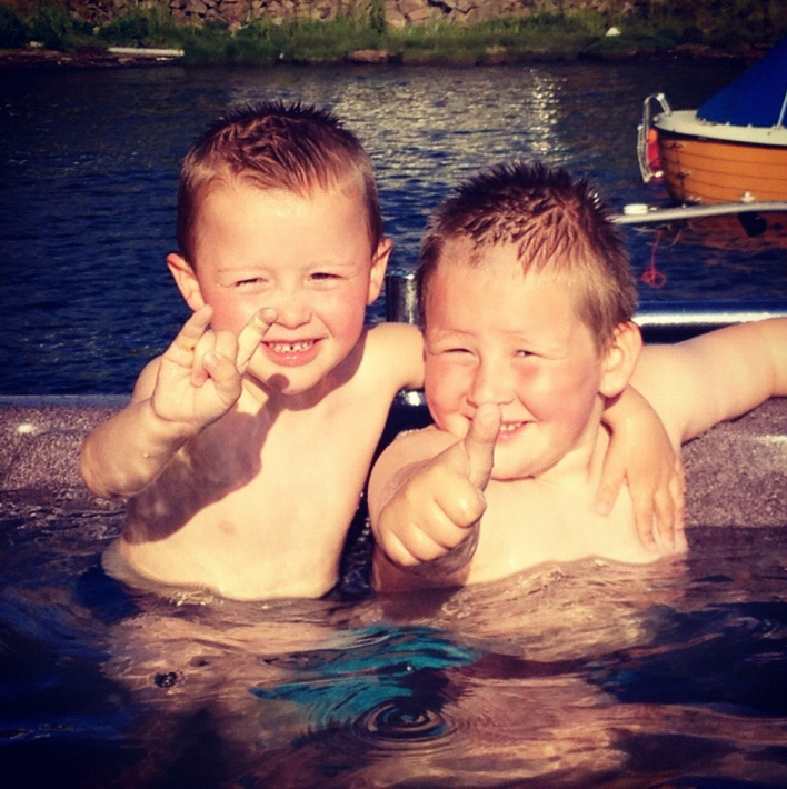 To gutter som koser seg i et basseng en sommerdag